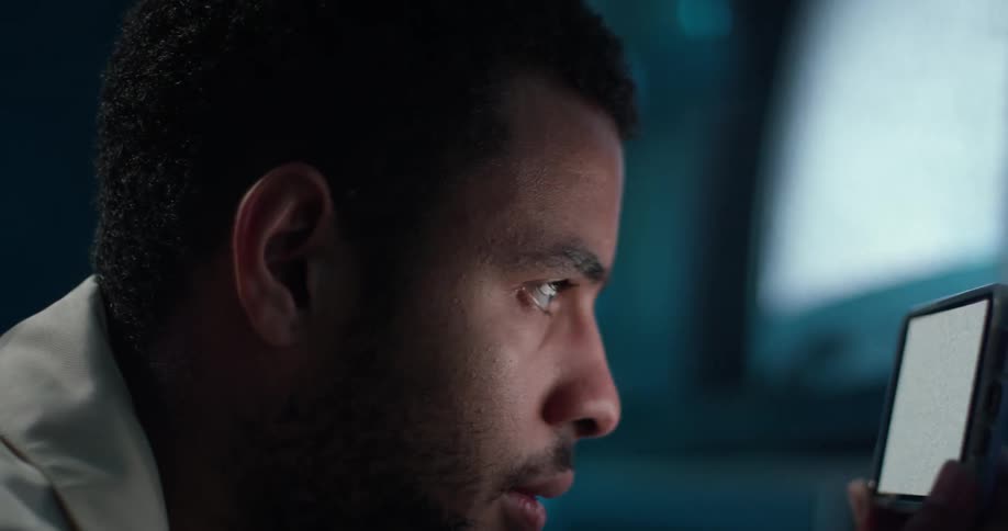A man leans down to closely watch static flashing on a smartphone