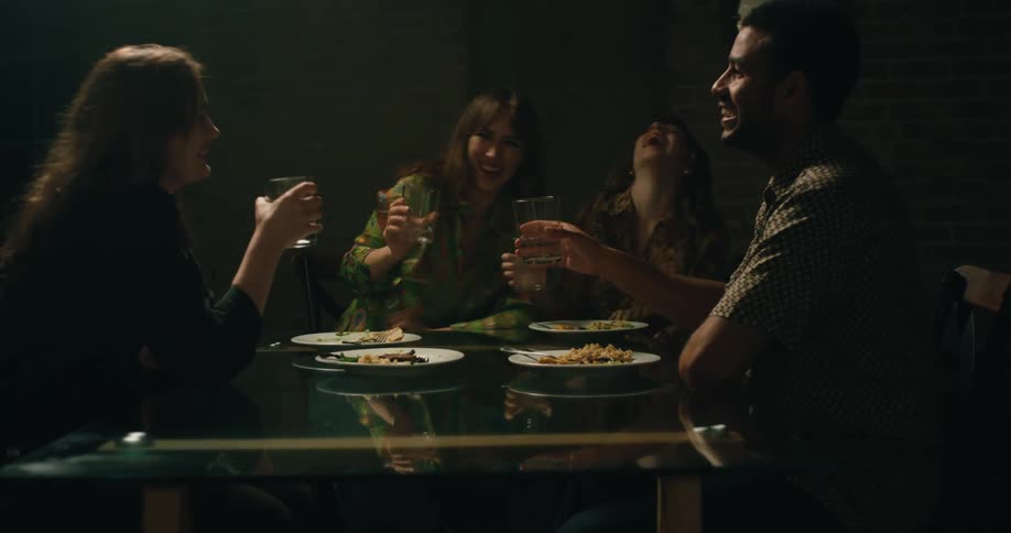 Friends sitting together for a meal toast and then laugh