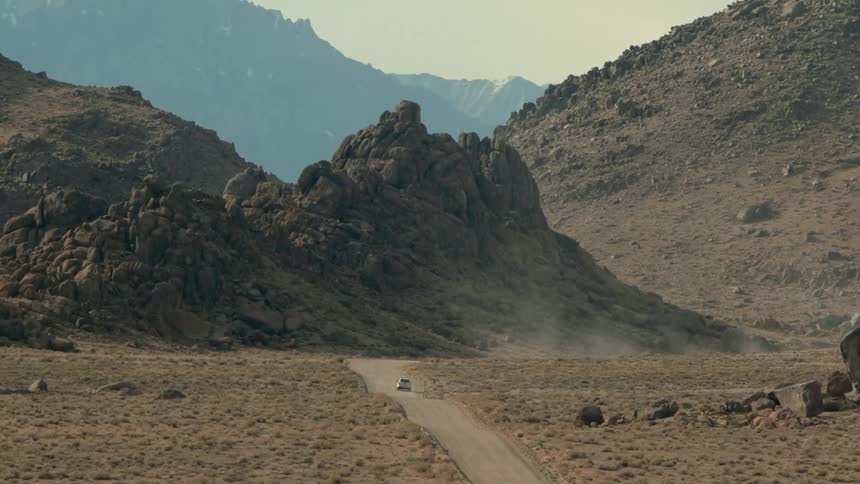 A car is driving on a dirt road in the wilderness