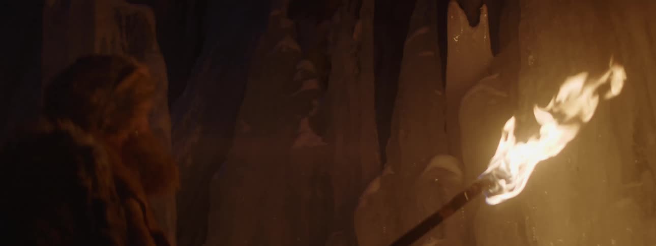 A man is waving a torch in the ice filled cave