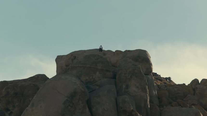 A man is hiking on top of a mountain at dusk