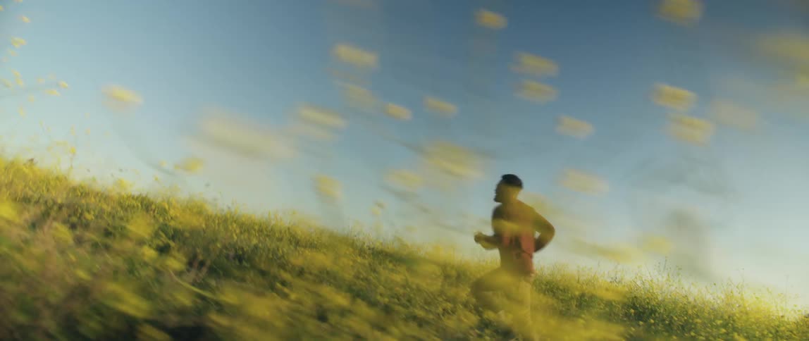 A man is jogging outdoors in an open grass field