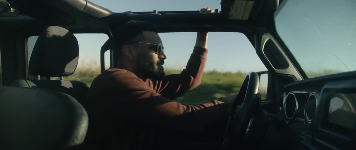 A man is driving his car in a rural area at dusk