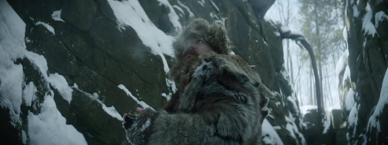 A man is outdoors by a bonfire in winter