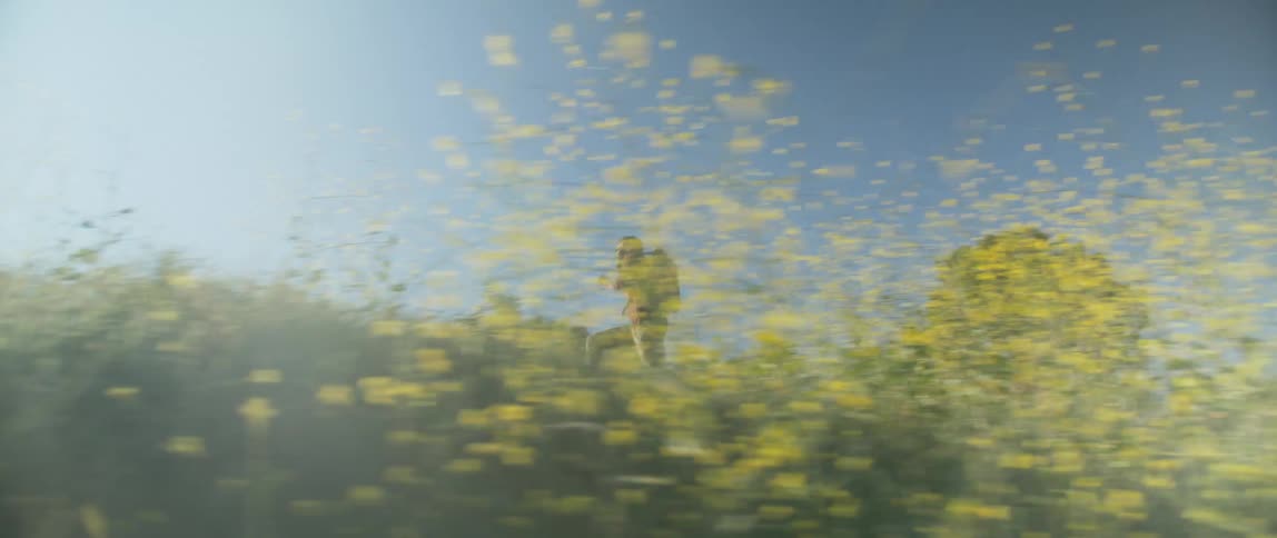 A man is jogging through a grassland field during the day