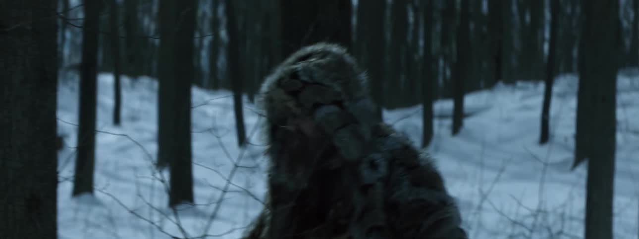 A man cuts down vegetation as he walks through a snowy forest