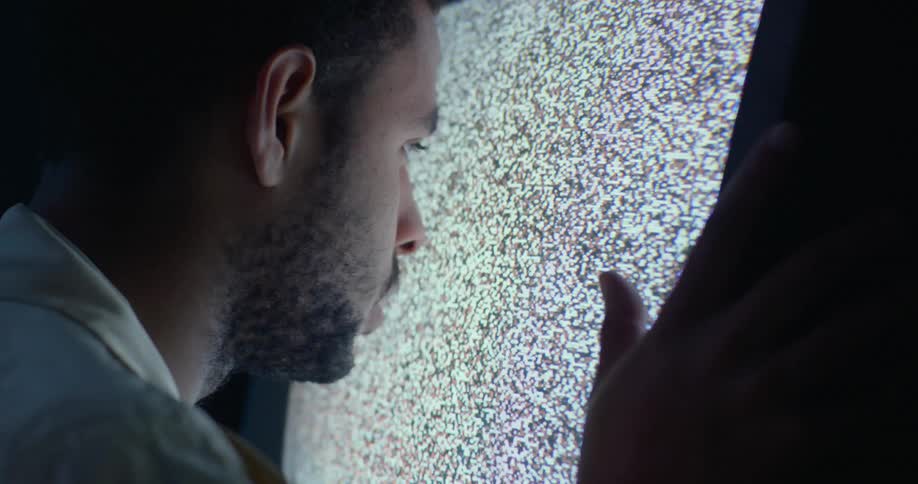 A man is leaning against the static filled television