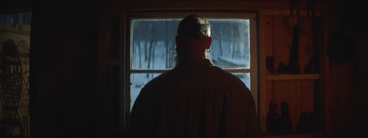 A man is standing in his garage and is looking through a window