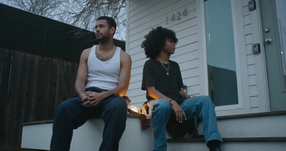 Man and woman are sitting on the steps outside of their house