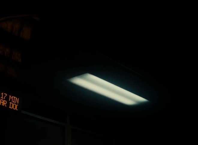 A light fixture hands near a rolling display screen with time information