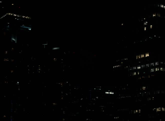 Tall buildings illuminated by lights from their windows in a metropolis at night
