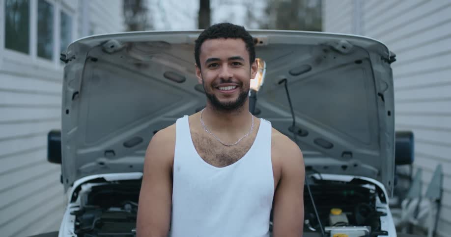 Young man is standing in front of vehicle
