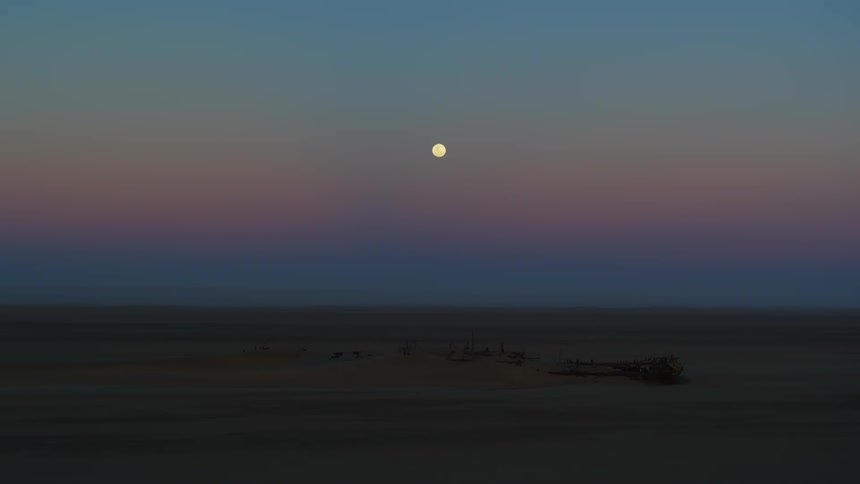 Sunset over the desert in Namibia with the faint outline of a shipwreck