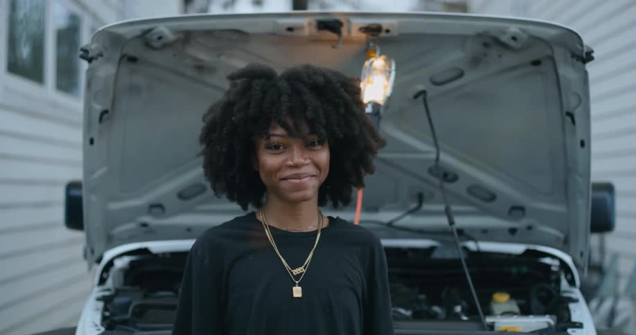 A woman is standing outdoors next to a parked car