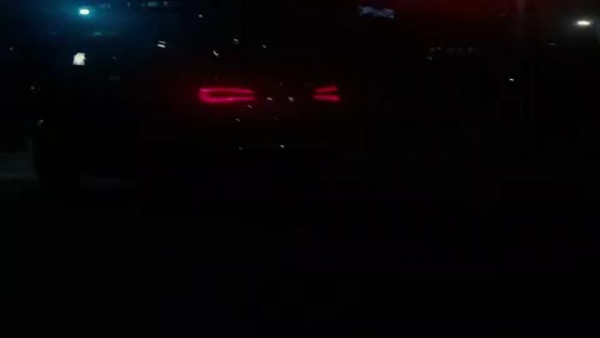 A car is driving through a downtown city at night