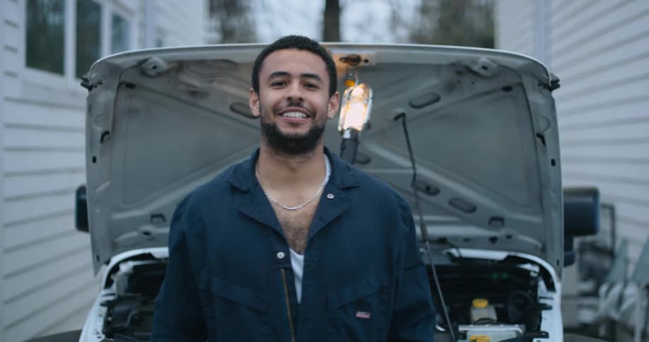 A man is standing outdoors in front of his car