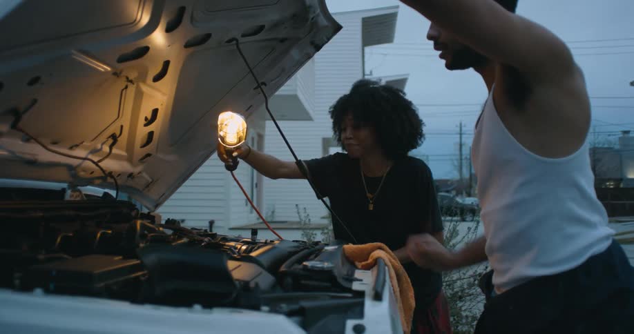 A man and woman are fixing the vehicle in the daytime