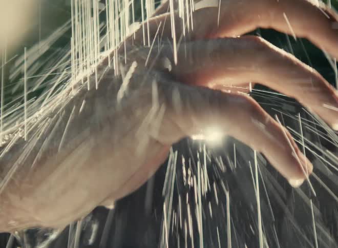 Close up of a hand getting wet under a stream of water showering down outdoors