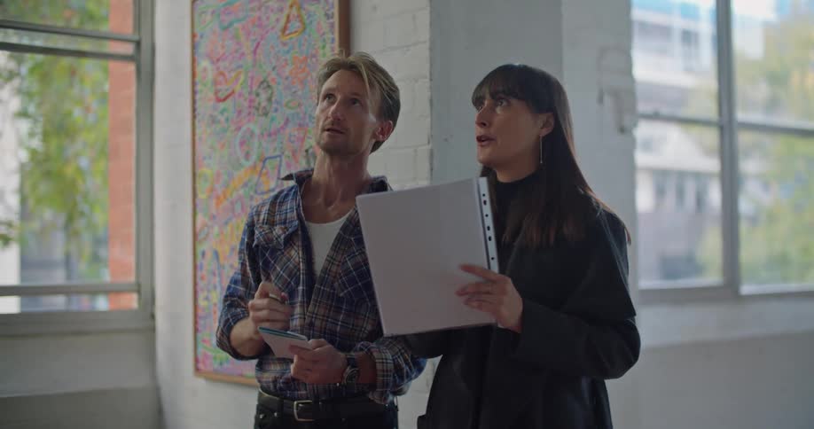 A man and woman standing in a loft discussing the space and design