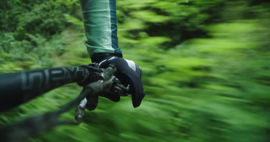 Close up of the handlebar of a mountain bike pedaling on a trail through the forest