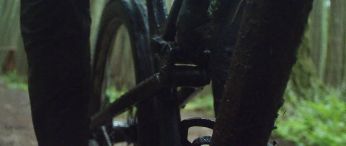 A person riding a mountain bike splashes through a mud puddle as suspension compresses