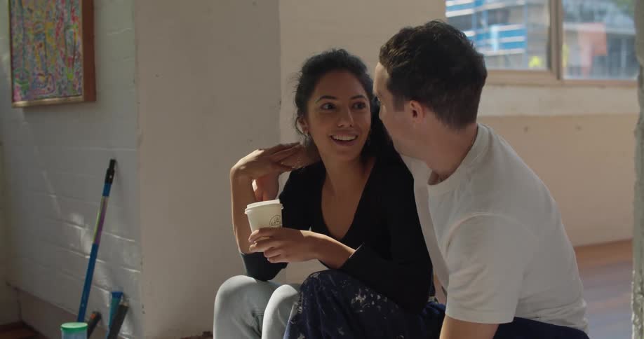 A couple cuddle and talk while taking a break from painting the room