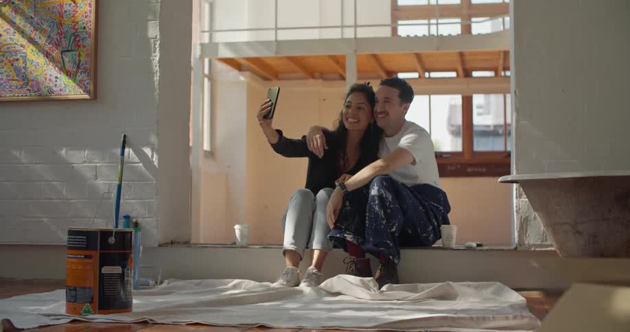 Young couple take a rest from painting the house to take a selfie together