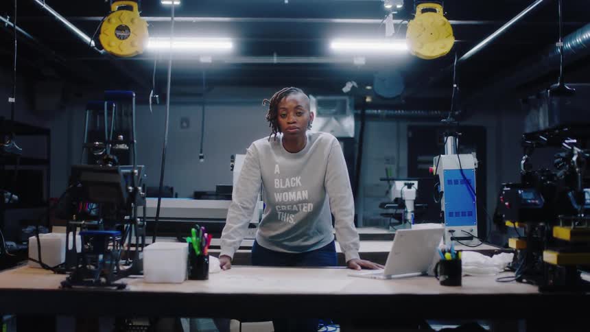 A woman is a warehouse by a desk and laptop