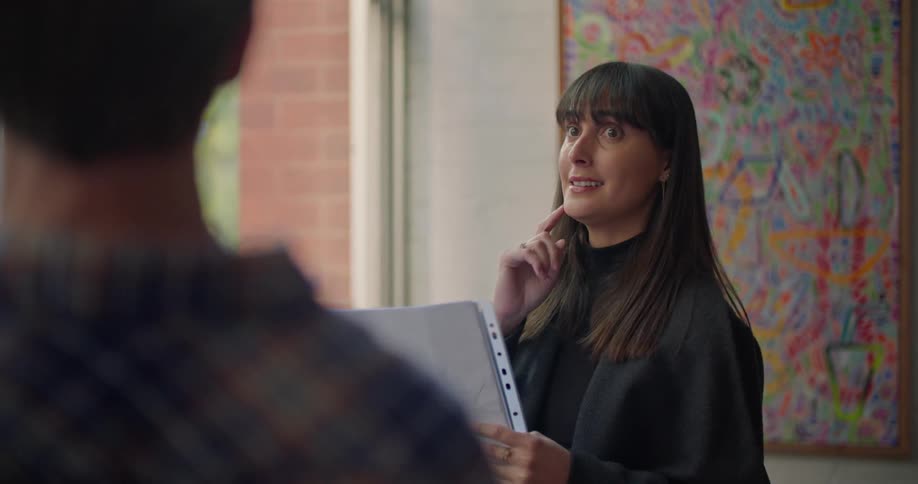 Woman holding a document talks to a man about the windows on a house