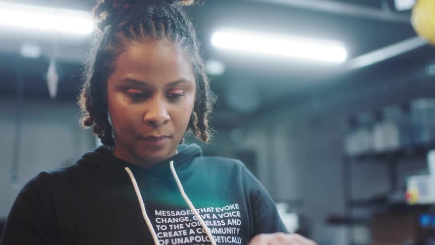 A woman screen prints a t shirt in a shop