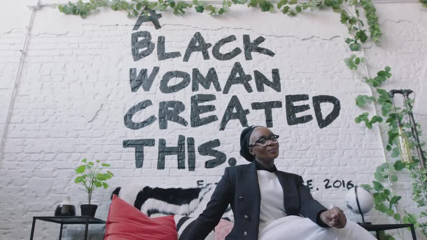A woman is posing in front of a wall