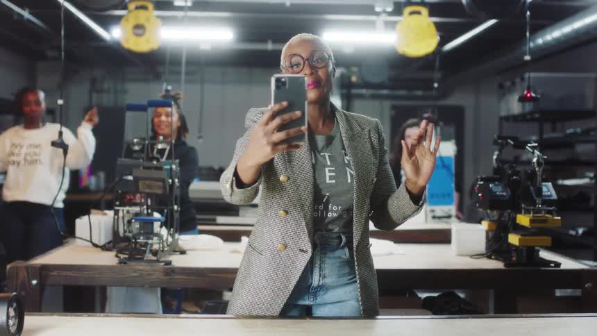 A woman uses a smartphone to record herself with three other women in a recording studio