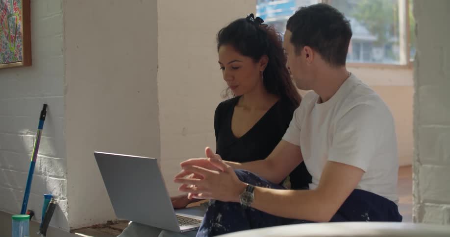 A man and woman talk and look at a laptop together