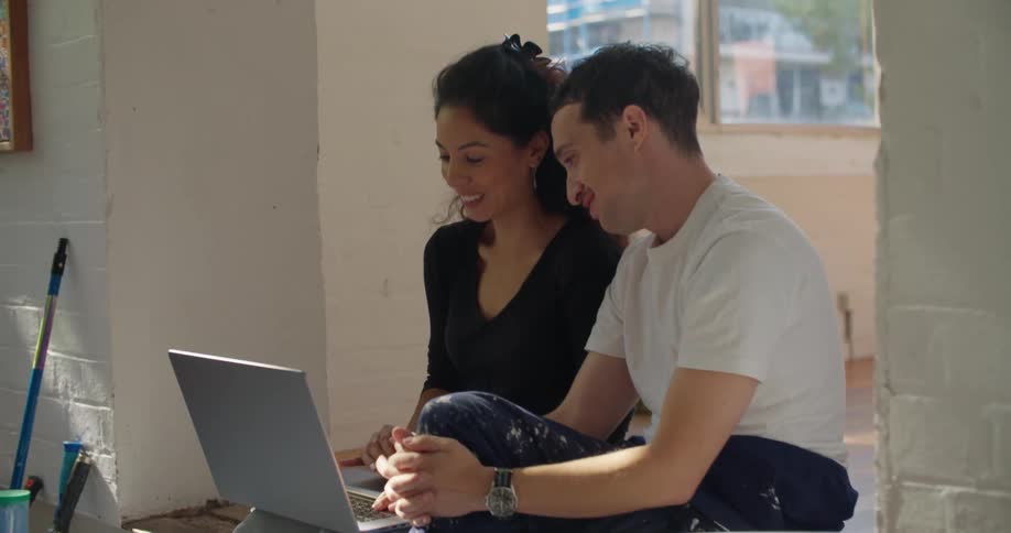 Man and woman are sitting down and looking at a laptop