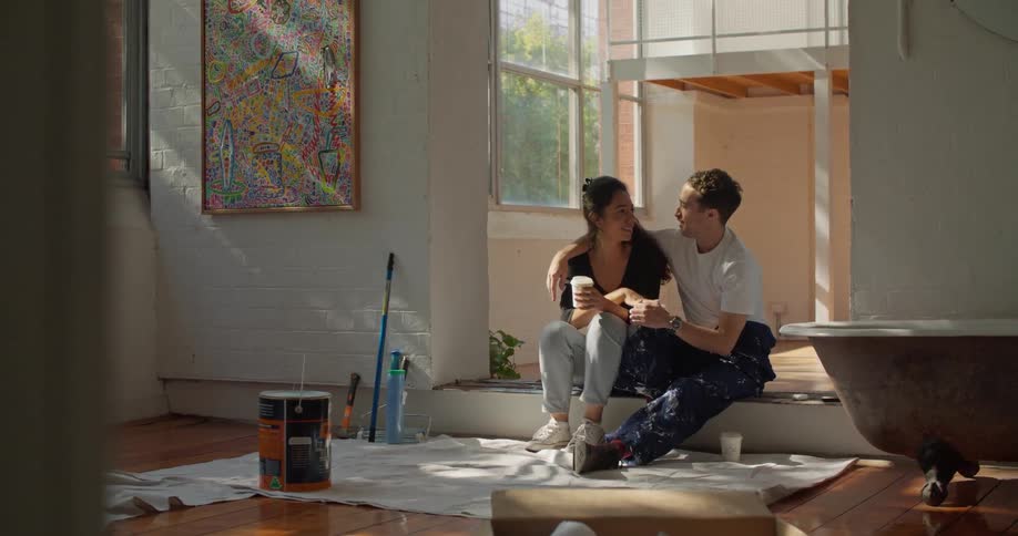 A couple is sitting on the floor of a house under renovation