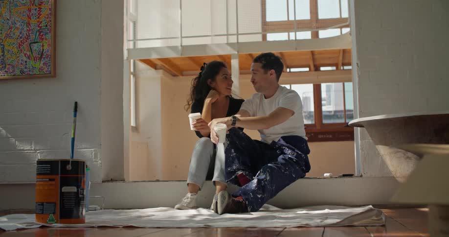 A man and woman sit with cups in the room