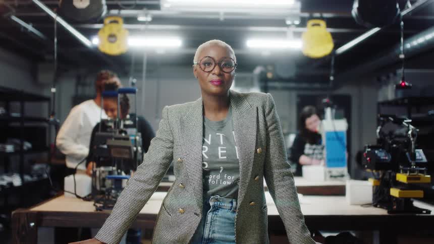 People work in the workshop as a woman poses