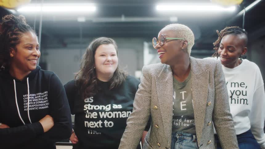 Four female friends are smiling in a room