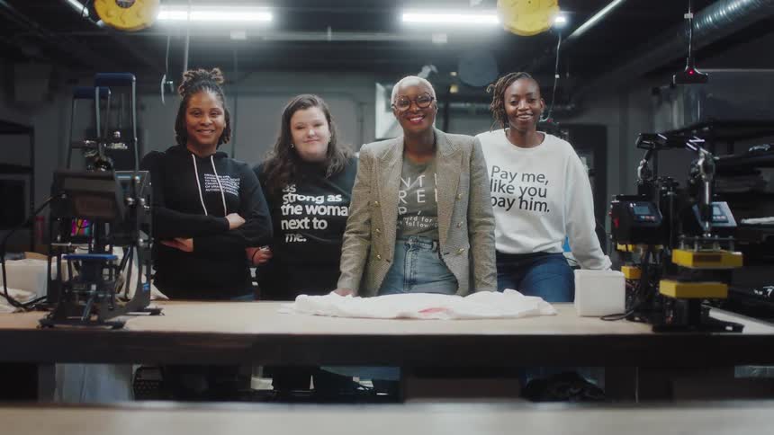 A group of four women are standing in a room together