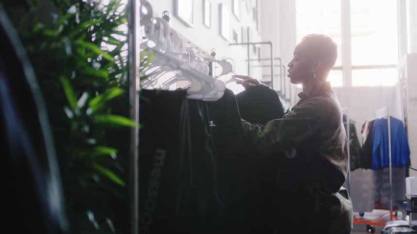 An employee places a shirt on a clothing rack in a store