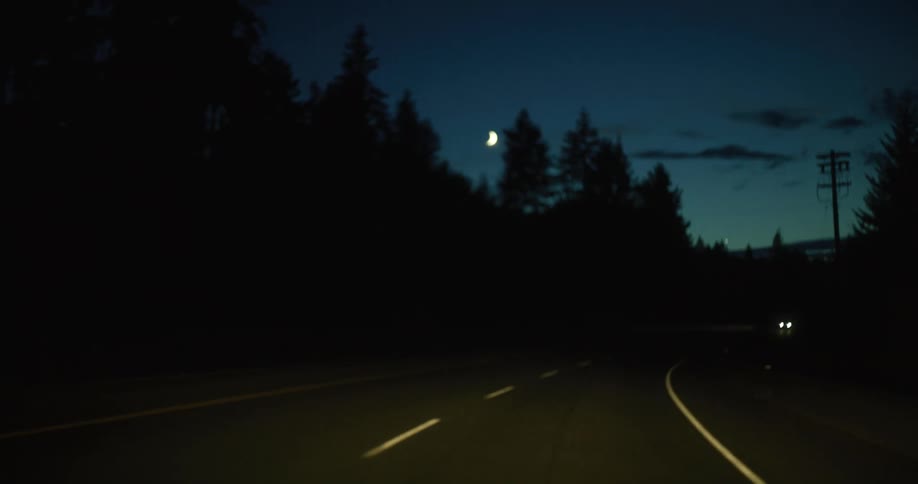 Cars are driving on a road in a rural area at nigth