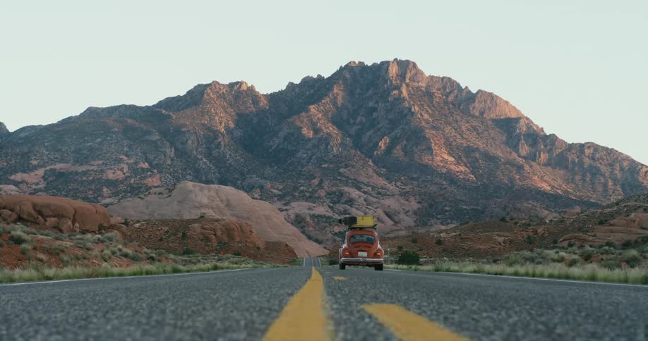 A vehicle travels along a road through a countryside during the day