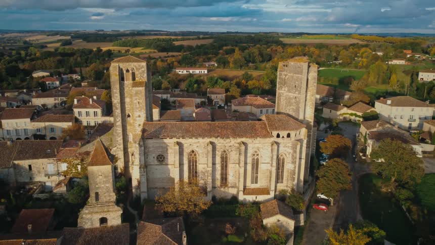 A large church looms over the surrounding buildings in a rural town on a cloudy day