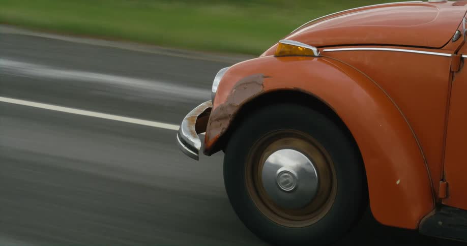 A vintage car travels along a road during the day