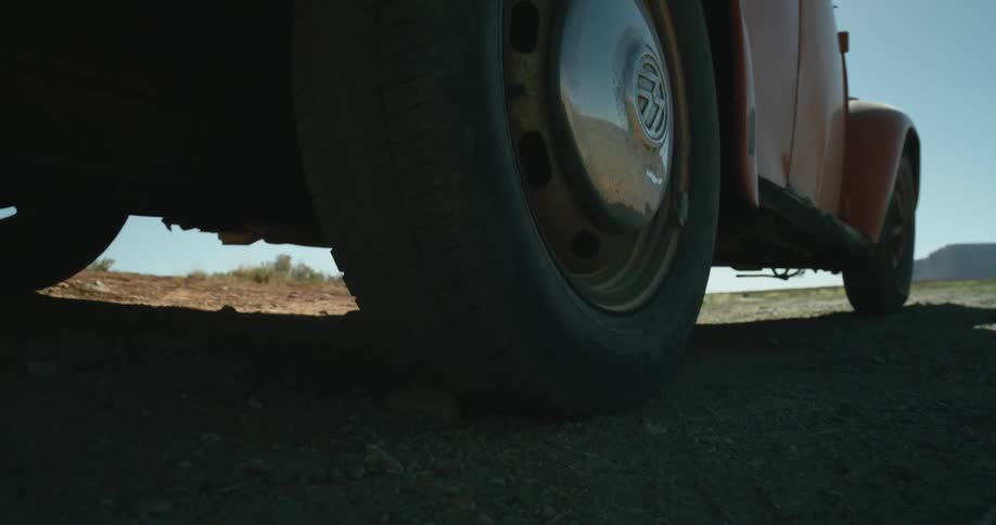 A car kicks up dust behind it as he travels offroad through a grassland during the day