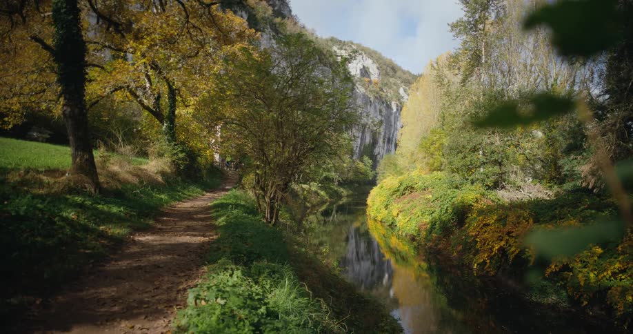 River flowing near a dirt path near the mountains at morning
