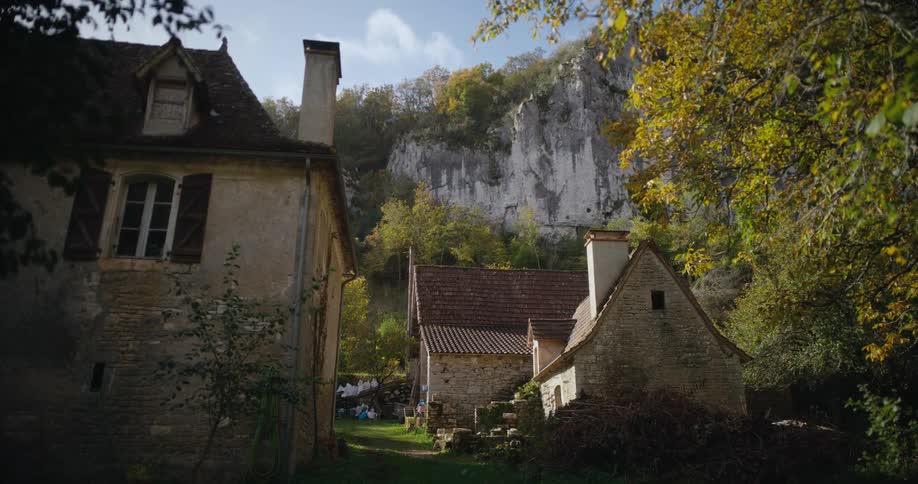 A picturesque cottage sits below a cliff in the countryside