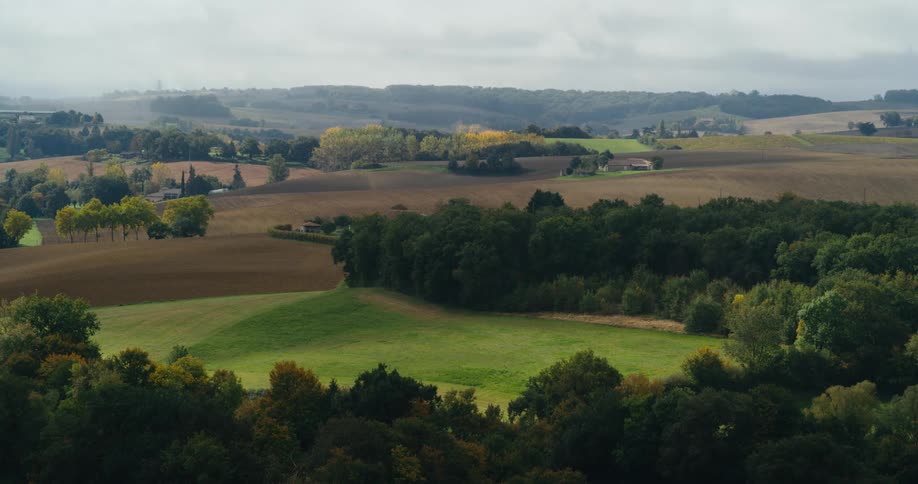 A hilly countryside dotted with houses on a cloudy day