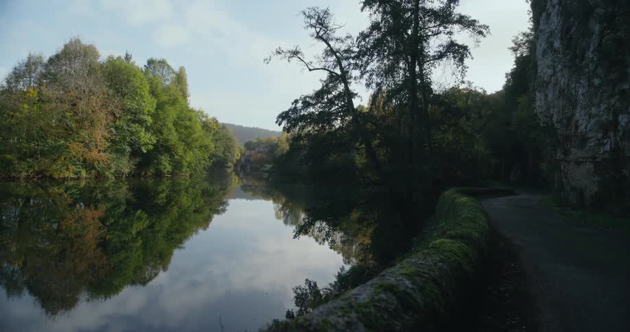A river is surrounded by trees and landscape is in the distance