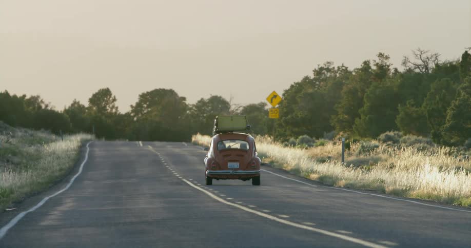 A car is driving through a rural area at dusk